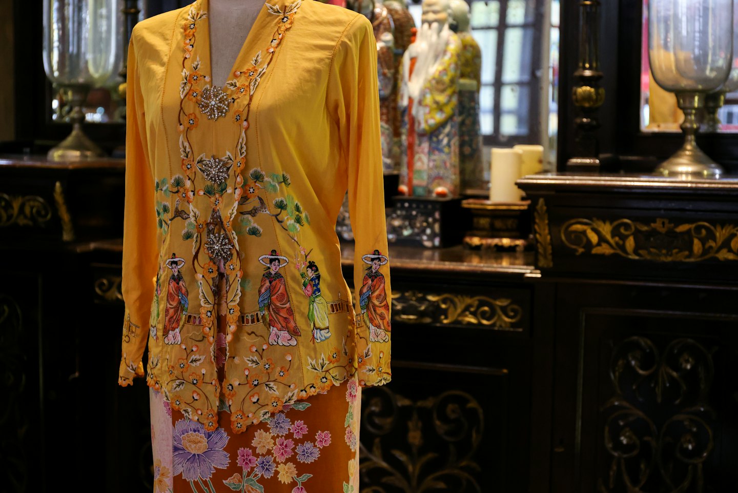 Embroidered yellow blouse with brooches and patterned sarong.